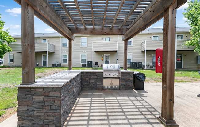 a covered patio with a grill in front of an apartment building