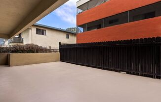 a view of the back of a building with a black fence and an orange building in the