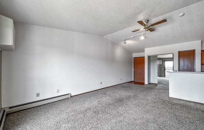 an empty living room with white walls and a ceiling fan