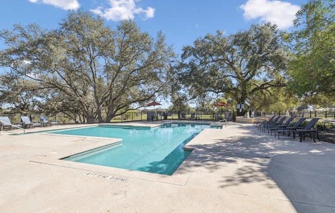 a swimming pool with chairs around it and trees