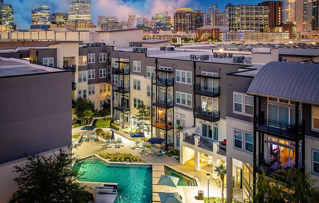 A view of a pool and apartment complex at dusk.