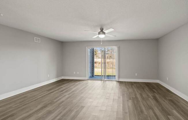 A room with a ceiling fan and sliding glass doors.