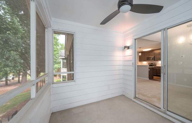 A room with a ceiling fan and sliding glass doors.