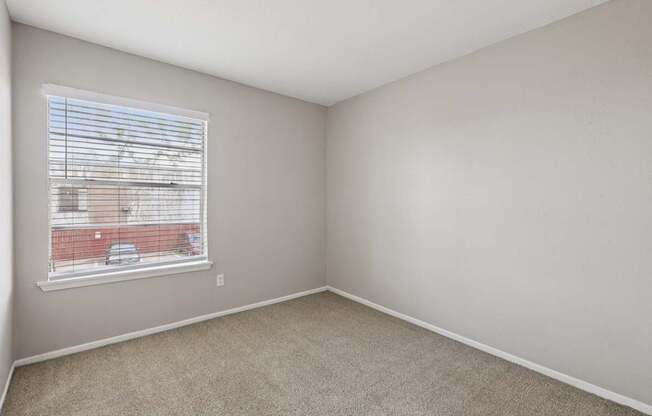 A room with a window and a view of a red building outside.