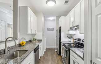 A kitchen with white cabinets and a granite countertop.