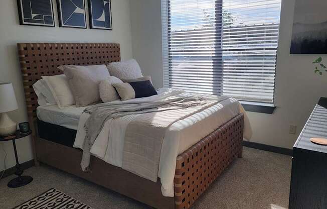 A bedroom with a bed, nightstand, and window with blinds.