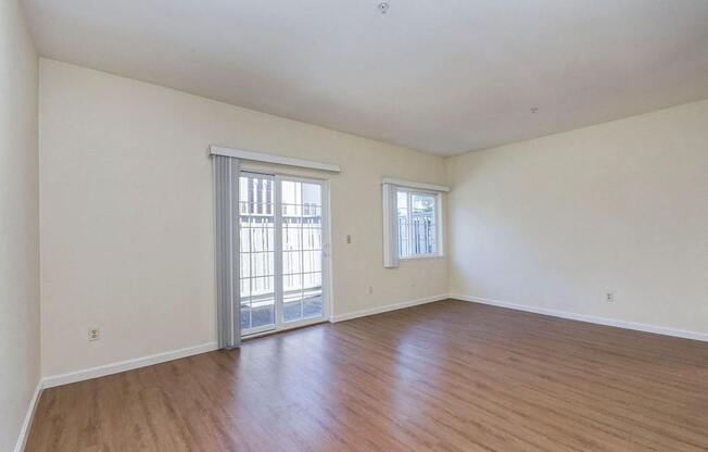 A room with wooden floors and two windows.