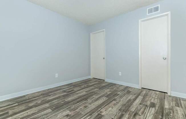 A room with a wooden floor and two doors.
