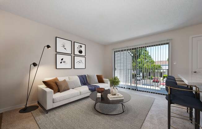 an open living room with a couch and a coffee table   and a balcony