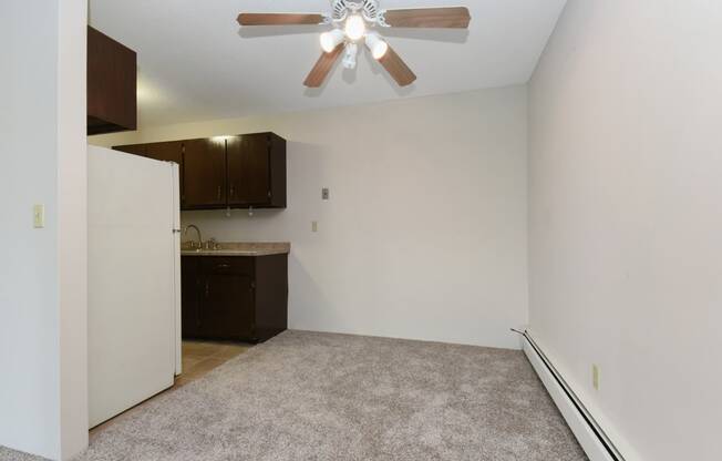 an empty living room with a ceiling fan and a kitchen. Roseville, MN Rosedale Estates