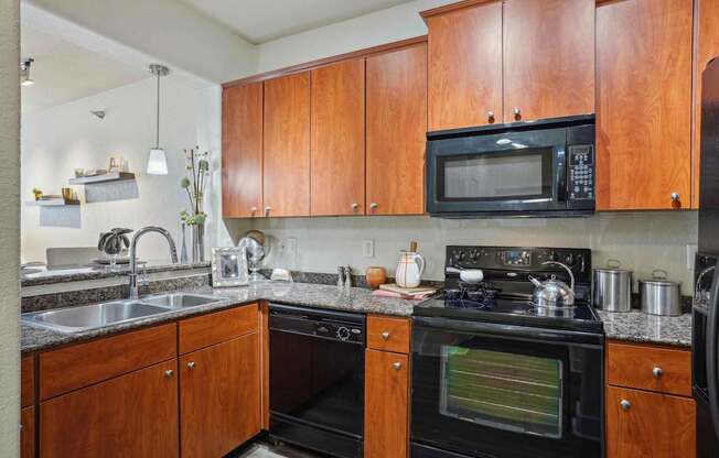 A kitchen with wooden cabinets and a black microwave.