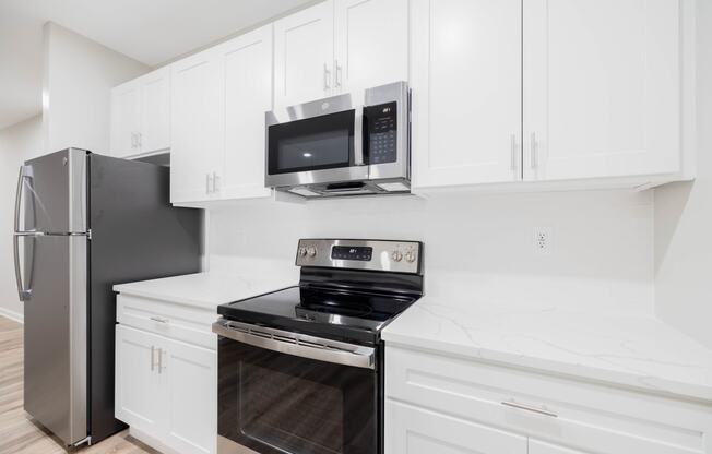 a kitchen with white cabinets and black appliances and a stainless steel refrigerator