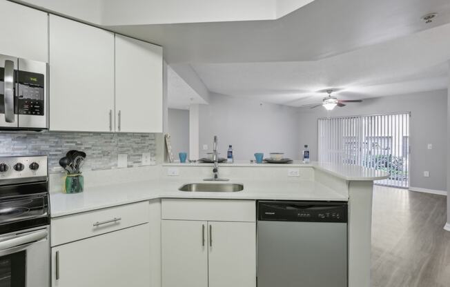 a kitchen with white cabinets and a sink and a stove at Pembroke Pines Landings, Florida