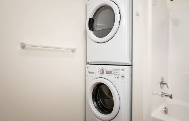 a white washer and dryer in a white laundry room with a white sink