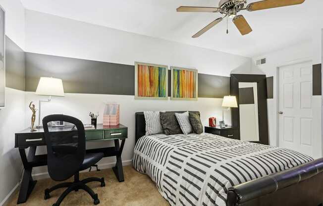 A bedroom with a bed, desk, and chair.