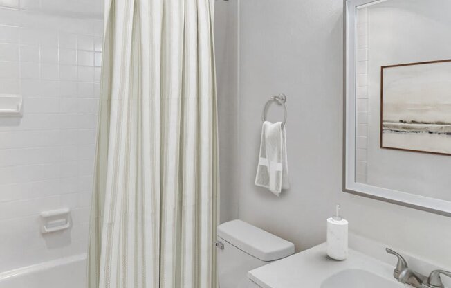 A white bathroom with a toilet, sink, and shower.