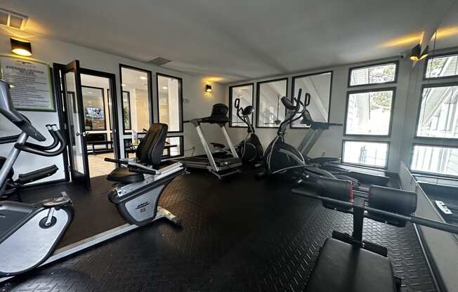 a gym with cardio equipment and windows in a building