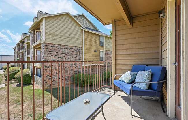A patio with a blue cushioned chair and a table.