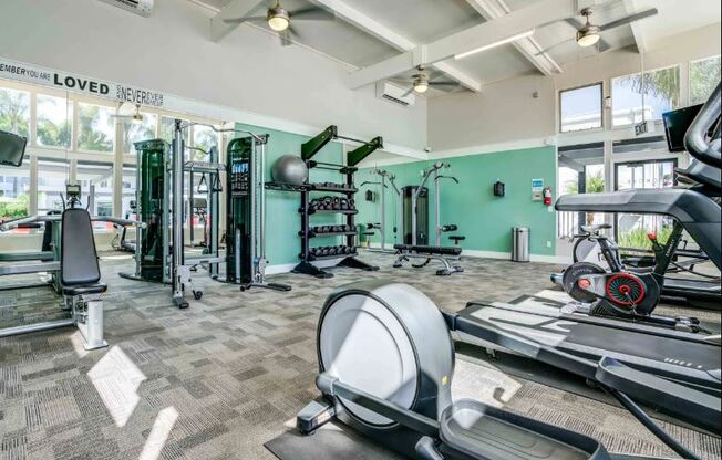 A gym with a variety of equipment including treadmills, weights, and exercise machines.