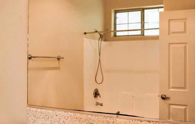 View of bathroom with vanity, large mirror with lighting, and reflection of tub shower combo, with well lit window