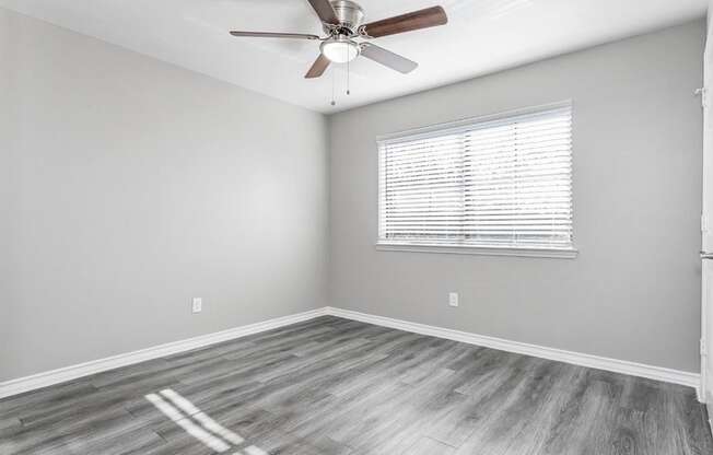 A room with a ceiling fan and a window with blinds.
