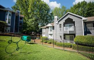 A playground with a green slide in the foreground and apartment buildings in the background.