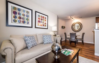 a living room with a couch coffee table and a dining room table in the background at Misty Ridge Apartments, Virginia, 22191