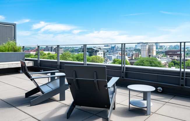 a terrace with two chairs and a table with a view of the city in the background