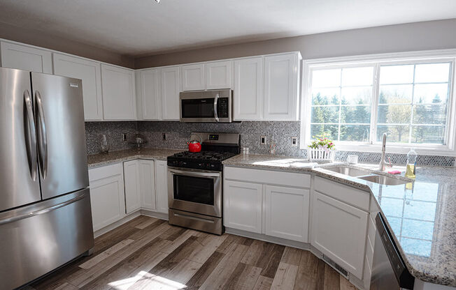 a kitchen with white cabinets and stainless steel appliances