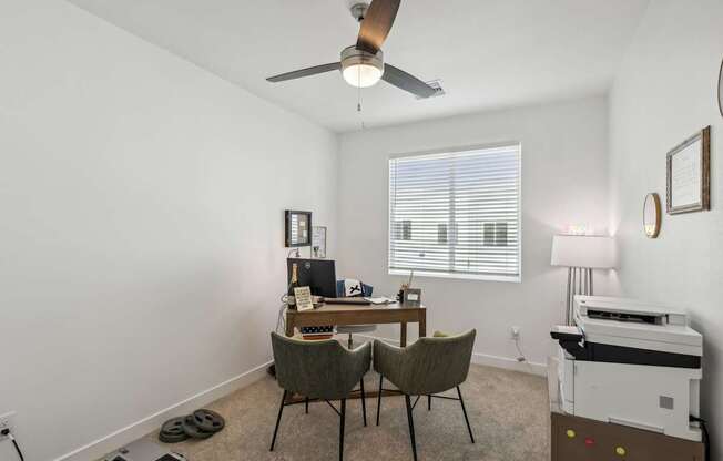 A room with a desk, chairs, and a printer.