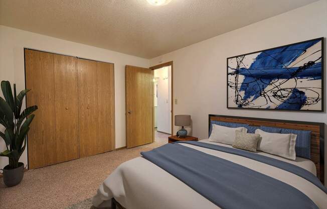 Fargo, ND Saddlebrook Apartments. a bedroom with a large bed and a potted plant