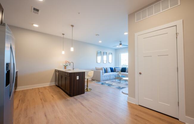 a kitchen and living room with white walls and wood floors