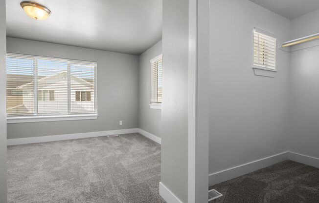 a bedroom with a large window and carpeted flooring