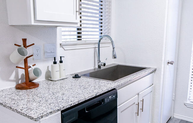 A kitchen with white cabinets and a granite countertop.