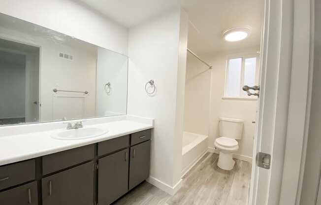 Spacious full bathroom with counter space, ample cabinet storage, sink, towel racks, shower, toilet, and frosted glass window.at Summit, Pocatello, ID