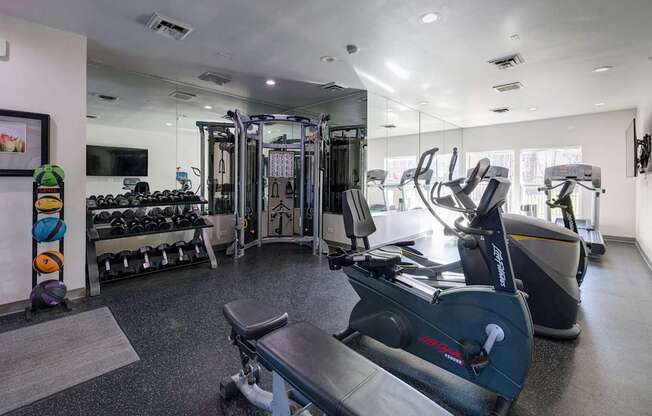 A gym with a variety of equipment including treadmills, weights, and exercise machines.