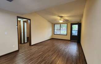 an empty living room with wood floors and a ceiling fan