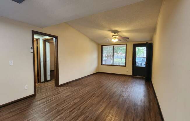 an empty living room with wood floors and a ceiling fan
