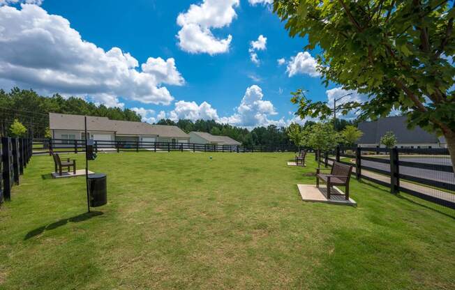 a park with benches in front of a fenced in field