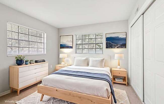 A bedroom with a bed, nightstands, and pictures on the wall.