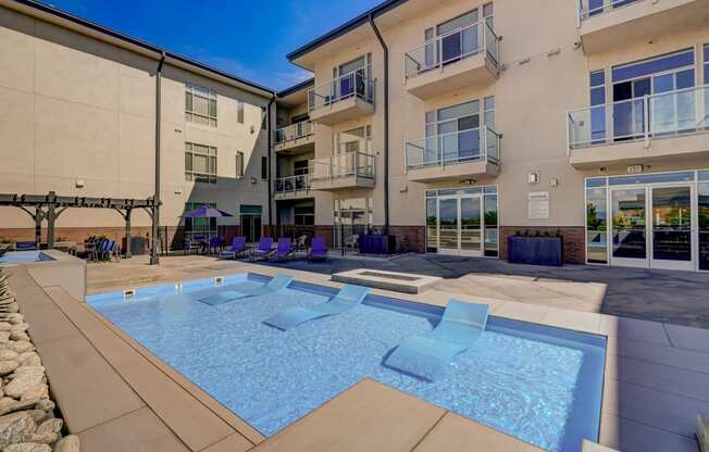 an apartment building with a pool and chairs in front of it