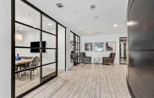 A modern living room with a wooden floor and glass walls.
