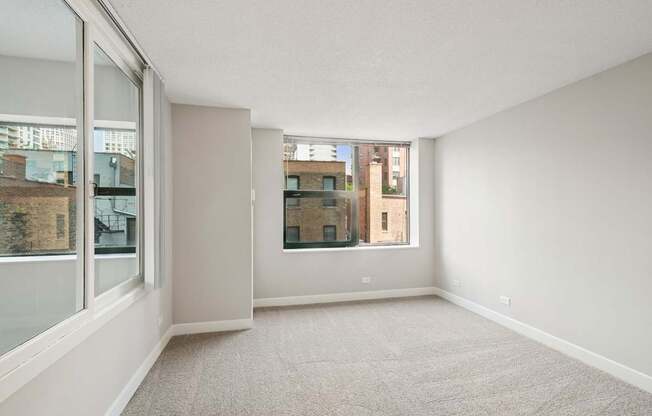 A spacious room with a carpeted floor and large windows.