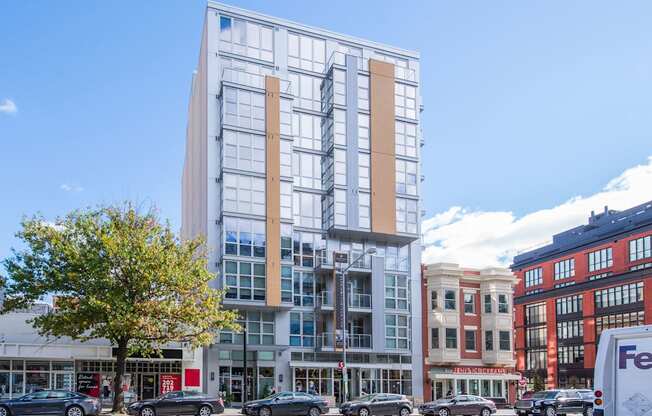 A modern glass building stands in front of a row of older buildings.