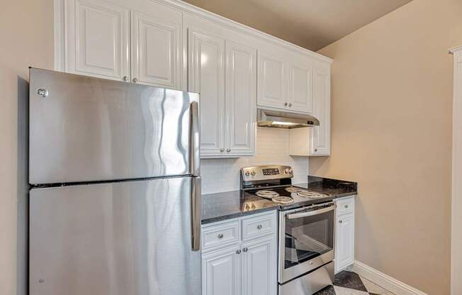 A kitchen with a stainless steel refrigerator, oven, and range hood.