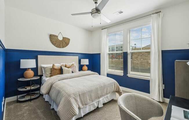 a blue and white bedroom with a bed and a ceiling fan