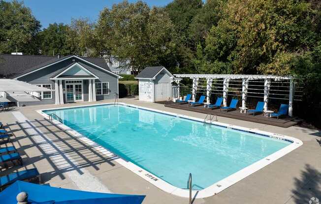 A swimming pool surrounded by trees and a small building.