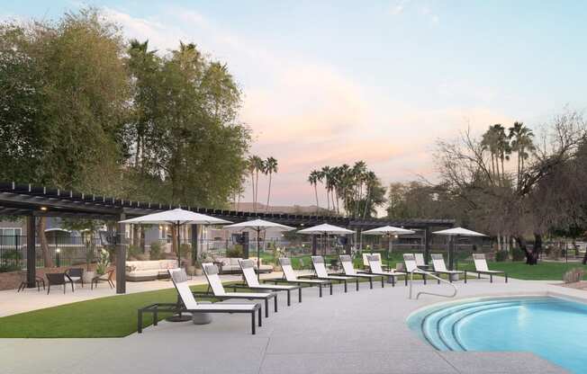 a pool with lounge chairs and umbrellas next to a pool
