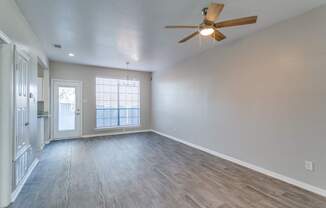 A room with a ceiling fan and wooden flooring.