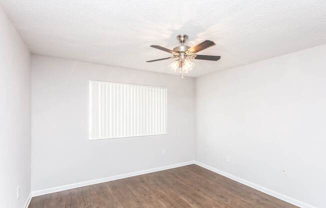 A room with a ceiling fan and wooden flooring.